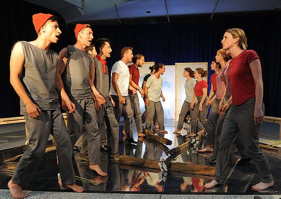 Auf einer Bühne stehen sich Männer und Frauen gegenüber, die sich etwas zu rufen.